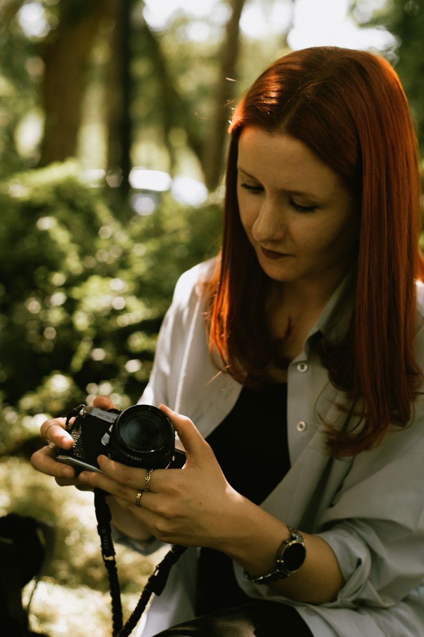 Travel photographer inspecting analog medium format camera outdoors