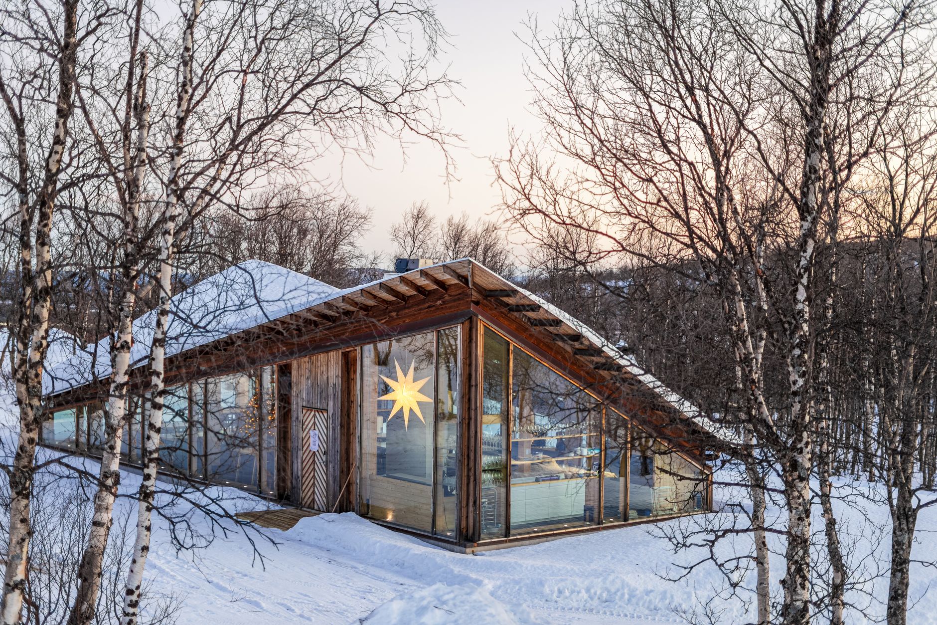 Modern wooden cabin overlooking snowy fjord landscape